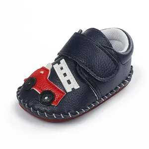 Détail de chaussure bébé bleu marine avec camion de pompiers et semelle cousue