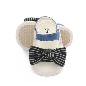 Nahaufnahme von Baby-Laufsandalen mit einer schwarz-weiß gestreiften Schleife und weicher Sohle