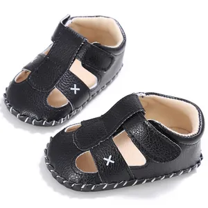 Detailansicht schwarze Baby-Sandalen mit weißem Kreuzmuster und Klettverschluss.