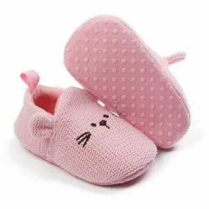 Close-up of pink knitted baby walking shoes with cute cat face design and soft sole.