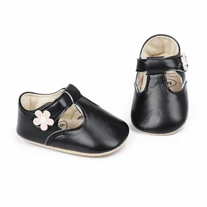 Detailed view of black faux leather baby girl shoes with cute pink flower decoration