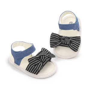 Nahaufnahme atmungsaktiver Baby-Sandalen mit schwarz gestreifter Schleife und Denim