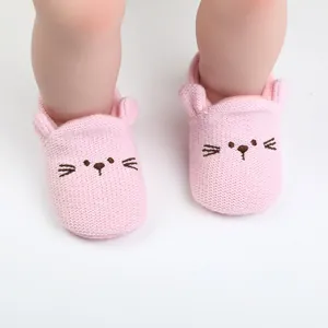Detailed view of cute pink knitted baby walking shoes with embroidered cat face design