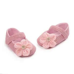 Detalle de lindos zapatos de bebé rosa con flor a cuadros y decoración de botón.