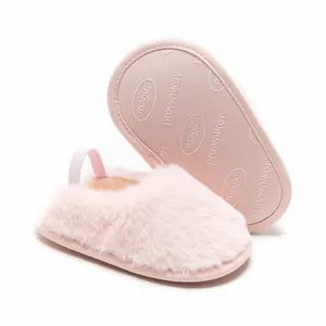 Primo piano dettagliato di pantofole neonato rosa pelose con suola antiscivolo.