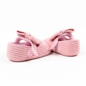 Close-up detail showing the soft pink ribbed texture and large bow on baby shoes.