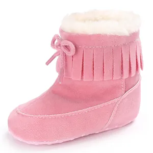 Detailed view of a pink suede baby snow boot featuring fringe trim and warm white plush lining