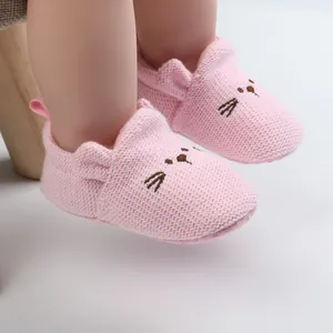 Close-up of soft knitted pink baby shoes with cute embroidered kitten face