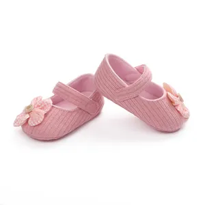 Zapatos de bebé rosa para niña con detalle de flor y textura suave de tela de canalé.