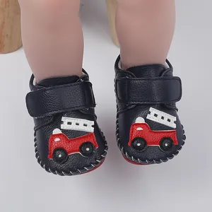 Gros plan de chaussures de marche pour bébé en cuir bleu avec applique de camion de pompier