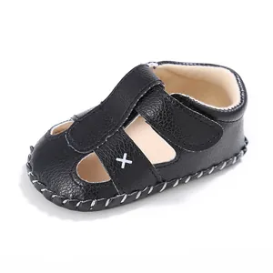 Detail einer schwarzen Baby-Sandale aus geprägtem Leder mit weißem Kreuz