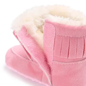 Close-up detail of pink baby snow boots with soft faux fur lining and stylish fringe