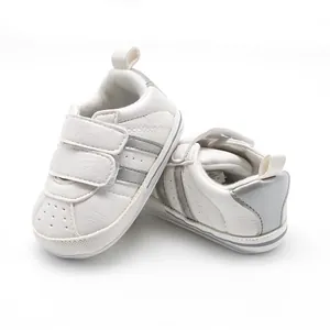 Detail view of white baby walking shoes with silver stripes and velcro straps.