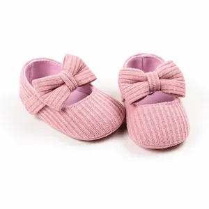 Close-up detail of pink ribbed knit baby girl shoes with large bow decoration