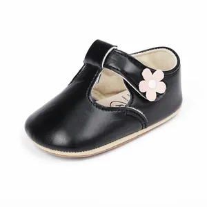 Λεπτομέρεια μαύρου βρεφικού παπουτσιού με λουράκι T και διακοσμητικό ροζ λουλούδι