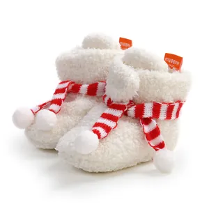 Close-up of cozy white fuzzy baby boots with festive red and white striped scarf detail