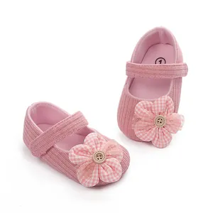 Vista detallada de zapatos de bebé rosa para niña con adorno de flor a cuadros.