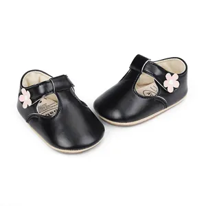 Detail of black infant princess shoes featuring a pink flower and soft rubber sole