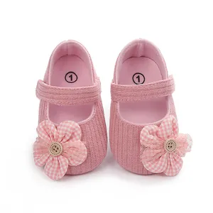 Detalle de zapatos de bebé rosa para niña con flor de cuadros y botón de madera.