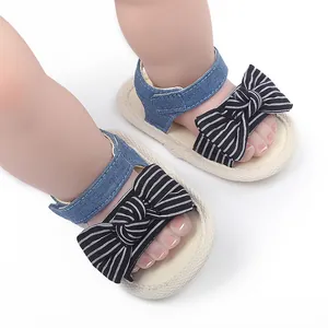 Nahaufnahme von Baby-Lauflernsandalen mit Denim-Riemen und gestreiften Schleifen
