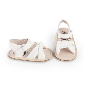 Close-up detail of white baby walking sandals featuring a soft decorative bow-knot design