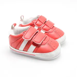 Detailed view of red baby sports walking shoes with white stripes and velcro.