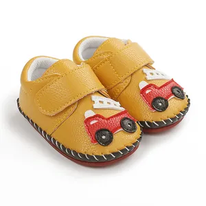 Gros plan de chaussures bébé jaunes avec un motif de petit camion de pompiers rouge brodé