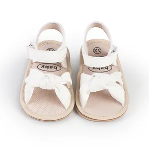 Detailed view of white infant walking sandals with large decorative bow on front