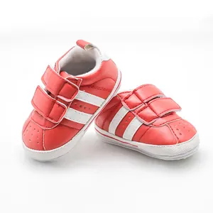 Detailed view of red and white infant walking shoes with double hook-and-loop straps