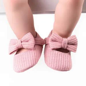 Close-up macro view of pink ribbed knitted baby princess shoes featuring a soft decorative bow.