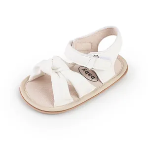Close-up of white baby pre-walker sandals featuring a soft sole and decorative bow