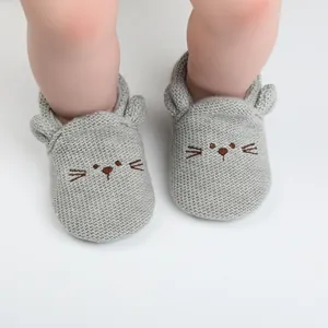 Detail view of gray knitted baby walker shoes with cute cartoon cat face and soft soles