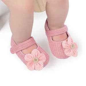 Vista detallada de zapatos rosa de pana para bebé con un adorno de flor de cuadros