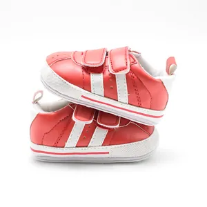 Side view of red infant walking shoes featuring white stripes and non-slip rubber soles.