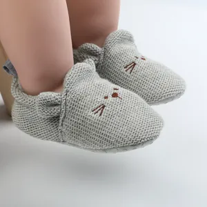 Close-up detail of grey knitted baby walking shoes featuring a cute cartoon cat face design