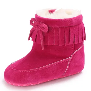 Close-up of pink baby snow boots with decorative fringe tassel and warm white faux fur lining