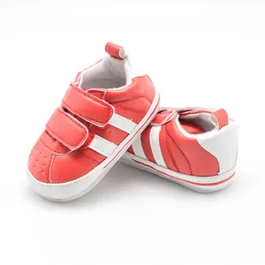 Macro detail of red baby walking shoes with white stripes and non-slip rubber sole