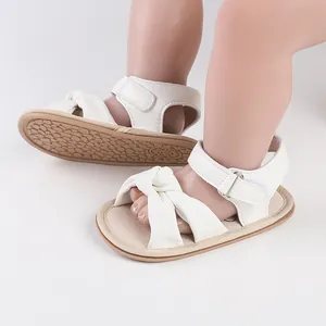Close-up view of white baby walker sandals with a knot design and non-slip rubber sole.