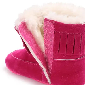 Close-up of pink infant snow boots showing warm faux fur lining and fringe detail.