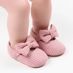 Nahaufnahme der rosa gestrickten Prinzessinnenschuhe für Babys mit einer großen Schleife