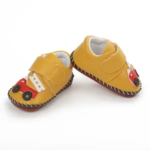 Gros plan de chaussures de marche pour bébé jaunes avec motif voiture et couture main.