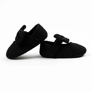 Macro view showing the soft knitted texture of black baby shoes with bow details