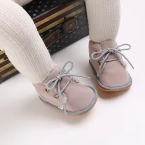 Nahaufnahme von rosa Baby-Lernlaufstiefeln mit warmem Fellfutter und Schnürsenkeln.