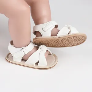 Close-up view of white baby pre-walker sandals with knot detail and non-slip sole.