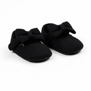 Close-up of black ribbed baby walking shoes featuring a decorative bow design on white background.