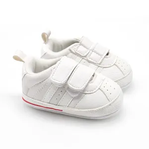 Close-up detail of white baby sneakers with dual velcro straps and soft flexible sole
