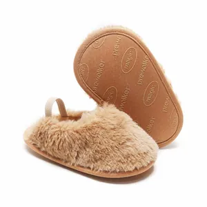 Dettaglio di pantofole per neonati in peluche marrone con suola antiscivolo morbida.