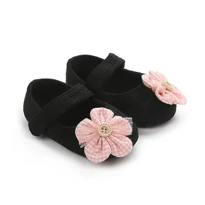 Detalle de zapatos de punto negros para bebé con decoración de flores a cuadros rosas