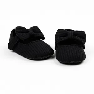 Detailed close-up view of black ribbed fabric baby girl princess shoes with large bow.