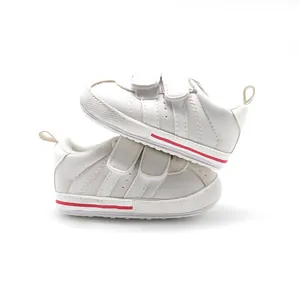 Side view of white baby pre-walker sneakers with double strap and red stripe detail.